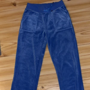 Blå velourbyxor Juicy Couture XS - Blåa mjukisbyxor från Juicy Couture, med bred resår och snörning i midjan. Byxorna har stora fickor fram och bak, samt broderad JC-logga på ena fickan. Helt som nya, har själv aldrig använt byxorna. Storlek xs men passar som S också! Kontakta mig ifall man vill ha mer bilder på byxorna, ifall man är intresserad eller om man har frågor.💞