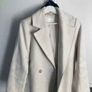 Vit kappa från H&M  - Vit kappa från H&M stl XS. Den är använd men fortfarande i bra skick. Säljer den för 350kr+frakt men går att pruta något.