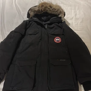 Svart Canada Goose Expedition dunjacka - Tja, säljer min svarta Canada Goose jacka som är perfekt för vinter då den är väldigt varm och skön. Om det är några funderingar så är det bara att kontakta mig så ska jag svara så fort som möjligt 