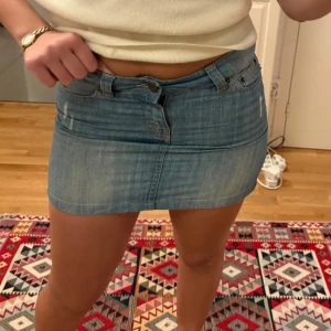 Kort jeanskjol  - Lågmidjad kort jeanskjol med slitna detaljer och en lätt tvättad look. Står ingen storlek skulle säja s/m 