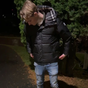 Svart pufferjacka från Burberry - Säljer en riktigt snygg och trendig svart pufferjacka från Burberry. Jackan har en stor huva, dragkedja och tryckknappar framtill samt Burberry-logga på ärmen. Jackan går även att göras om till en väst med hjälp av Zips i ärmarna. Perfekt för kalla dagar och riktigt snygg streetstil! Säljer för att den är för stor för mig (ej jag på bilderna).