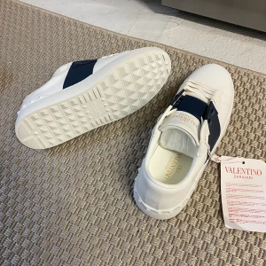 Valentino Garavani - Snygga vita sneakers från Valentino Garavani med bred mörkblå rem över vristen || Storlek:43 || Köpt här på Plick för 4500, säljer då dem inte passa. Priset är nedsatt då skolådan är sönder!