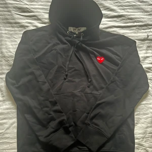 Svart hoodie Comme des Garçons Play S - Svart hoodie från Comme des Garçons Play i storlek S. Tröjan är helt oanvänd tagsen är dog avdragna. Skrov vid fler funderingar !!!!