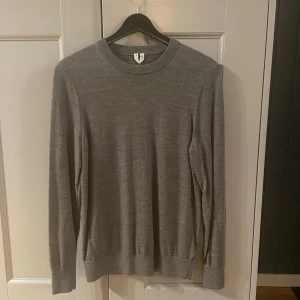 Grå stickad tröja XS - En enkel och stilren grå stickad tröja från arket i storlek XS. Tröjan har rund halsringning och långa ärmar, perfekt för lager-på-lager. Mjuk och skön känsla tack vare det stickade materialet. Passar dig som gillar minimalistisk och clean look.