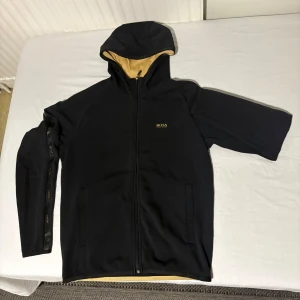 Svart/guld Hugo Boss (og) zipphoodie  - Tagit hand om den bra. Den är i jättebra skick.                         Storleken är S men kan också passa M 