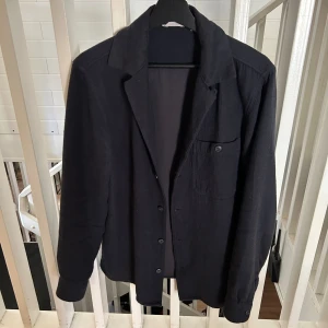 Navy overshirt från Dobber, S - Navy overshirt från Dobber i storlek S. Skjortan har klassisk krage, knappstängning framtill och en bröstficka med knapp. Materialet är mjukt och känns som bomull, perfekt för lager på lager. Stilren och enkel design som funkar till många outfits.