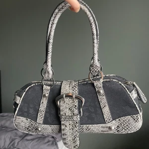 Y2k väska med ormskinnsdetaljer - Cool svart handväska med silverfärgade detaljer. Använt några gånger men fortfarande bra skick. Jätte fin och rätt rymlig. 