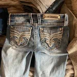 Rock Revival ljusblå bootcut jeans - Säljer ett par ljusblå jeans från Rock Revival med bootcut passform och midwaist. Det står midwaist fast själv tycker jag att dom är ganska low. Köpta för 1500 andvänt få tal gånger! 