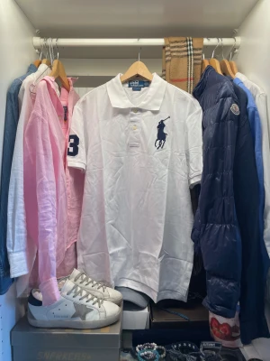 Vit polo från Ralph Lauren piké - Vit klassisk piké från polo från Ralph Lauren med stor marinblå broderad polospelare på bröstet och siffran 3 på ärmen. Perfekt stilren look till vardagen. Nypris ligger på runt 1400, är aldrig använd och har pristagarna kvar.                            Skriv vid frågor, priset är inte hugget i sten🤝