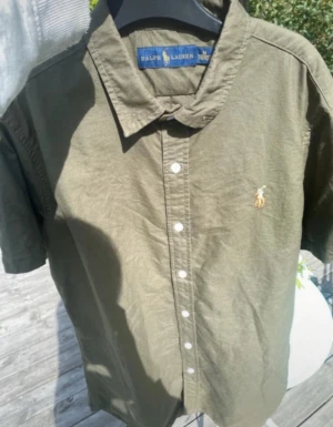 Ralph Lauren skjorta - Säljer en snygg olivgrön Ralph Lauren skjorta ( kortärmad). Den är i storlek m och sitter superbra på mig 180 cm. Kan visa bild vid intresse. Tveka inte att höra av dig. ☀️🦎