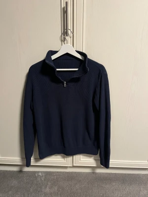 Marinblå stickad tröja  - Snygg marinblå stickad tröja med half zip och hög krage. Perfekt för dig som gillar stilren och avslappnad stil. Skick 10/10 säljs för 250kr pris kan diskuteras!