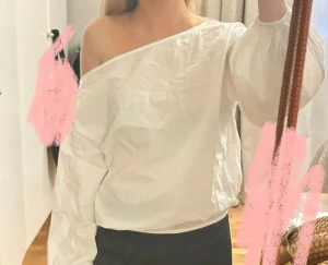 Vit offshoulder blus med puffärm - Säljer en vit blus med offshoulder-design och bred, asymmetrisk halsringning. Blusen har långa puffärmar med resår vid ärmslut och är tillverkad i ett lätt, krispigt bomullstyg. Perfekt för dig som gillar en trendig och luftig look.