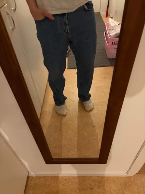 Blå jeans loose fit - Säljer ett par klassiska blå  jeans med loose fit och rak passform. Jeansen har knappgylf, fem fickor och är tillverkade i slitstarkt bomullsjeansmaterial. Perfekt för dig som gillar en avslappnad och tidlös stil.