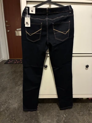 Mörkblå jeans från Rosebud Studio, stl 40 - Snygga mörkblå jeans från Rosebud Studio med kontrastsömmar och coola bakfickor med dekorativa detaljer. Modellen heter Avia jeans och är tillverkad i en mix av bomull, polyester och elastan för en bekväm passform. Perfekta för dig som gillar klassisk jeansstil.