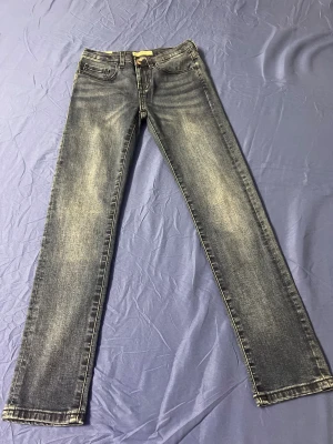 Slim fit jeans Sondre i gråblå tvätt - Slim fit jeans från Sondre i en snygg gråblå tvätt med slitningar. Klassisk femficksmodell, normalhög midja och smala ben. Jeansen har dragkedja och knapp framtill samt bälteshällor. Perfekta för dig som gillar en stilren och modern look.