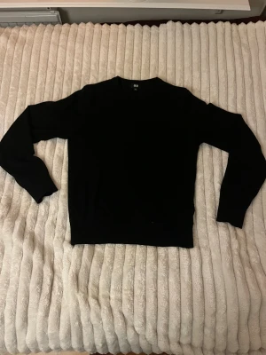 Svart stickad tröja från Uniqlo  - En stilren svart merinoulls stickad tröja från Uniqlo i storlek XS. Tröjan har rund hals och långa ärmar, Riktigt bra passform på tröjan. Skriv gärna om frågor eller fler bilder.