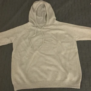 Ljusgrå hoodie med huva och snörning - En enkel och stilren ljusgrå hoodie med huva och snörning. Tröjan har långärmade raglanärmar och ribbad kant vid nederdelen och ärmsluten. Perfekt för chill dagar och passar till det mesta. Materialet känns mjukt och bekvämt mot huden.