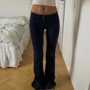 Mörkblå bootcut byxor - Säljer ett par mörkblå byxor/jeans med bootcut passform och låg midja. Byxorna har klassiska fickor fram och bak, samt bälteshällor.