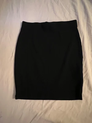Svart minikjol - Svart tight minikjol med lite ribbat material. Köpt på New Yorker. Använd fåtal gånger. Nypris: 119-129.