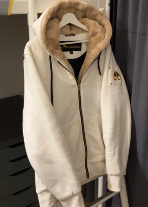 Vit och beige Moose knuckles bunny jacka - Säljer Vit Moose knuckles Bunny jacka/cardigan. Skön och håller dig varmt under vintern, hösten, våren. Köpte den från johnells och den är i bra skick