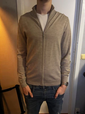 Matinique Tröja - Matinique tröja/zip-up i en beach/sand färg. Den är 100% merino och strlk L. Modellen på bilden är 193 och väger 82kg. Köpt för 800. Pris kan diskuteras.