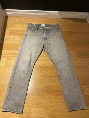 Grå Loose Chris jeans storlek 30/32 - Jag säljer ett par ljusgråa jack&jones jeans i storlek 30/32. Har en liten fläck vid vänster ficka som inte märks annars är dom i mycket bra skick. Skriv gärna frågor och kom med prisförslag!! 