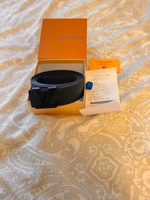 Svart Iv bälte - Svart Iv bälte med serie nummret 4169. Bältet är oanvänt och kommer med orginal box och kvitto. Bucklan/ loggan kan bytas ut mot sen silvrig logga