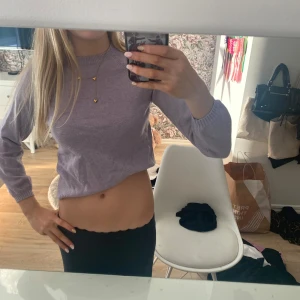 Ljuslila croppad stickad topp - Säljer en ljuslila croppad stickad topp med lång ärm och rund hals. Tröjan har en enkel och clean design som är lätt att matcha med olika outfits. Perfekt för dig som gillar en avslappnad men ändå trendig stil.