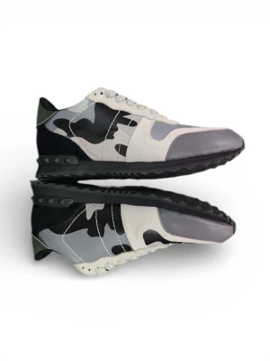 Valentino Rockrunner sneakers camo - Säljer ett par Valentino Rockrunner sneakers med grå, svart och vit camo. Skorna har coola nitar på sulan, snörning och detaljer i mocka och skinn. Snygg kontrast mellan olika material och färger, samt en unik camouflagemönstrad box som medföljer.