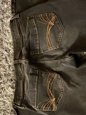mörkgrå jeans med broderade detaljer på bakfickorna - supersnygga mörkgrå jeans med broderade detaljer på bakfickorna, endast använda 1 gång!! säljer då jag aldrig använder dem, passar till vardagen❣️tveka inte att kontakta mig om du vill ha ytterligare bilder eller mått