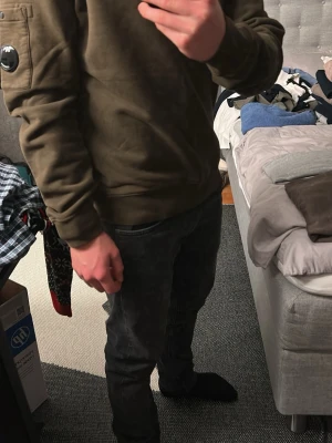 Olivgrön sweatshirt från C.P. Company - Säljer en olivgrön sweatshirt från C.P. Company med klassisk rund hals och lång ärm. Tröjan har en cool detalj med en svart lins på ärmen och en ficka med knapp. Materialet är mjukt och känns som bomull, passformen är normal.