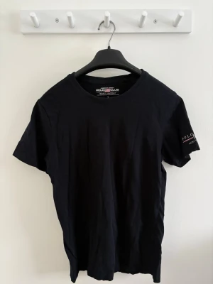 Herr mörkblå t-shirt   - Enkel jätte mörkblå (nästan svart) t-shirt från Polo Club Saint Vincent med tryck på ärmen. Klassisk rund hals och korta ärmar. Skön och mjuk i bomull, perfekt till jeans eller shorts. Snygg logga på ärmen för en clean look.