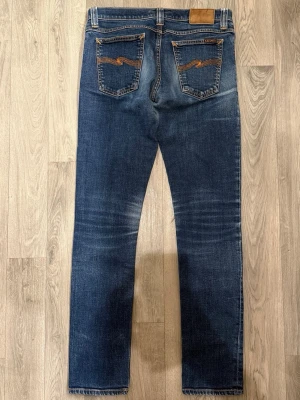 Nudie Jeans Tight Long John Jeans W29 L32 - Sjukt snygga blåa Nudie Tight Long John ’Org. Twill Rinsed’ jeans i mycket fint skick med snygg fade i storlek W29/L32. Mått - Midja: 38,5cm, Benlängd: 99,5cm. Modellen är 185cm & 63kg. Hör av dig vid funderingar!🤝