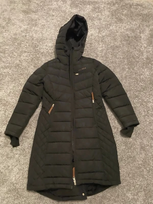 Ridkappa Jacson  - Hej! Säljer nu min ridkappa från Jacson då den inte används, den är svart i storlek S men är mer som XS ifall man har tjocka kläder under eller en säkerhetsväst. Den har hög krage, knapp uppning bak så de ska bli enklare och bekvämare att rida i, ficka på vänstra bröstet och vanliga fickor. Och så har den en räm med en knapp som ska sitta runt låren så jackan inte åker iväg eller åt sidan när man rider. Den är som helt ny inga skador. Den tvättad såklart innan den skickas! Köpt för 1600.