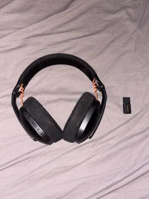 Cepter Trådlöst Gaming Headset - Cepter trådlöst gaming headset med USB-mottagare. Bekväma over-ear-kuddar i tyg, justerbar bygel och tydliga reglage på sidan. Headsetet ser ut att vara i gott skick med minimalt slitage. Perfekt för spel och långvarig användning. Har används 1 gång och man kan justera ljudet och sånt på sidan av headsetet.