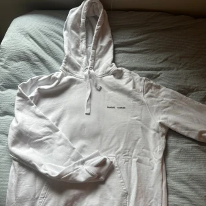 Vit hoodie från Samsøe Samsøe L - Vit hoodie från Samsøe Samsøe i storlek L. Klassisk modell med huva och snörning, samt känguruficka framtill. Diskret logga på bröstet. Mjuk och skön bomullsblandning, perfekt för chill dagar eller när du vill ha en clean look.  Nytt pris ca 1300kr