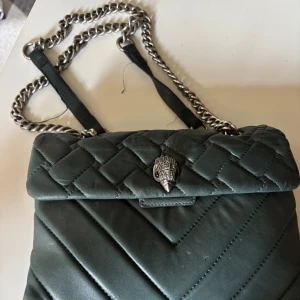 Quiltad grön axelväska från Kurt Geiger - Snygg grön axelväska från Kurt Geiger med quiltad design och silverfärgad kedja. Väskan har små slitningar på undersidan men inget märkvärdigt utan den är i väldigt bra skick!! Skriv prov för funderingar!💖💖