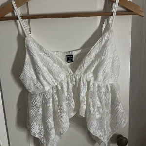 Vit spetsig linnetopp från SHEIN - Säljer en vit linnetopp från SHEIN i storlek XS. Toppen har tunna axelband, v-ringning och är gjord i ett skirt spetsmaterial med volangdetaljer. Perfekt för sommarens alla tillfällen! Den är inte direkt min smak tyvärr, använt endast när jag fick den ‼️