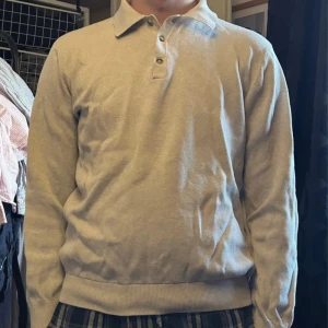 Beige pikétröja med lång ärm - Säljer en stilren beige pikétröja med lång ärm och klassisk krage. Tröjan har tre knappar framtill och ribbade muddar vid ärmslut och nederkant. Perfekt för dig som gillar en clean och enkel look. Pris kan diskuteras!