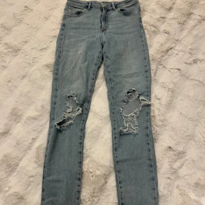 Ljusblå ripped jeans med skinny fit - Snygga ljusblå jeans med skinny passform och slitna detaljer på båda knäna. Perfekt för dig som gillar en avslappnad och trendig streetstil.