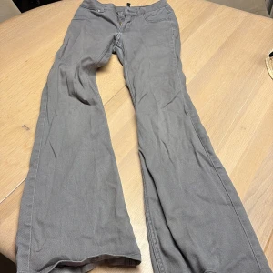 Grå bootcut jeans från H&M Divided - Snygga grå jeans från H&M Divided i storlek 34. Modellen har bootcut-ben, klassiska fem fickor, low waste och dragkedja med knapp framtill. Materialet är mjukt och bekvämt bomullstyg med lite stretch. Perfekt för dig som gillar en avslappnad och trendig look. Slitna längst ner se bilder 