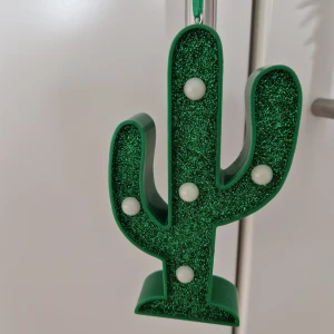 Kaktus LED-lampa - Dekorativ kaktusformad LED-lampa med grön glitterfinish och vita lampor. Batteridriven med strömbrytare på baksidan. Perfekt som nattlampa eller festdekoration. Produkten är i gott skick🌟