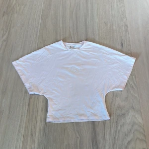 Vit loose topp från Nelly XS - Säljer en vit topp från Nelly i storlek XS. Modellen är loose fit med breda, korta ärmar och rund halsringning. Toppens material är mjuk bomull och den har en enkel, stilren look som är lätt att matcha med andra plagg.