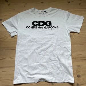 CDG T shirt - Vit t-shirt från Comme des Garçons med stor svart CDG-logga och text på bröstet. Nyskick!