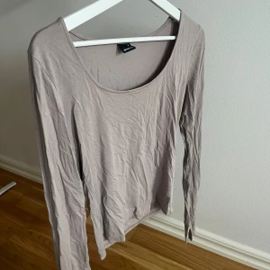 Beige långärmad topp - Säljer en enkel och stilren beige långärmad topp från Ginatricot. Toppen har rundad halsringning och är gjord i mjuk bomull som känns skön mot huden. Perfekt att styla med jeans eller kjol för en chill look.