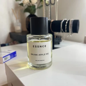Essnce Drunk Apple Pie Parfym - Modern Eau de Parfum med lekfullt namn och stilren design. Perfekt för dig som vill sticka ut med något unikt i parfymhyllan. Flaskans innehåll syns tydligt och etiketten är enkel och trendig.