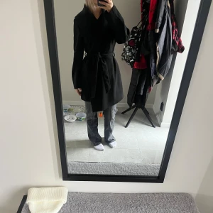 Svart kappa med bälte - Säljer en svart kappa från Vila med bälte i midjan. Använd ett fåtal gånger, pris kan diskuteras