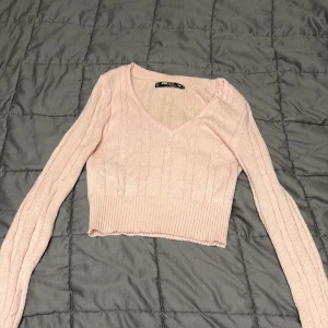 Ljusrosa croppad stickad topp new yorker  - Supersöt ljusrosa croppad stickad topp från new yorker. Toppen har v-ringning, långa ärmar och ribbade detaljer vid midjan och det är en magtröja men man visar inte mycket av magen