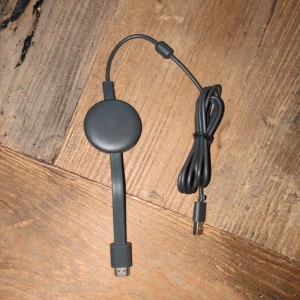 Google Chromecast - Google Chromecast streaming-enhet i svart. HDMI och USB-kabel medföljer. Enheten är i gott skick utan synligt slitage. Perfekt för att streama media från mobilen eller datorn direkt till TV:n.