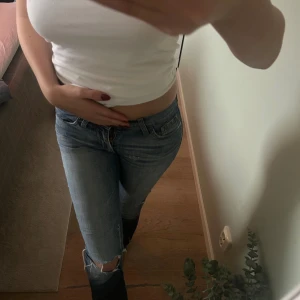 Blå jeans från Fornarina med slitningar - Säljer ett par blå jeans från Fornarina med snygga slitningar på knä och bakficka. normal passform och raka ben. Jeansen har en cool tvättad. 